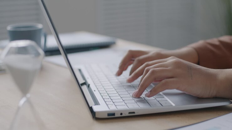 Frau schreibt am Schreibtisch auf Laptop