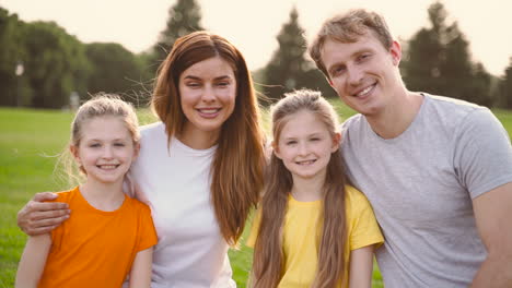 porträt einer glücklichen familie, die lächelt und in die kamera schaut, während sie gemeinsam zeit im park verbringt 1