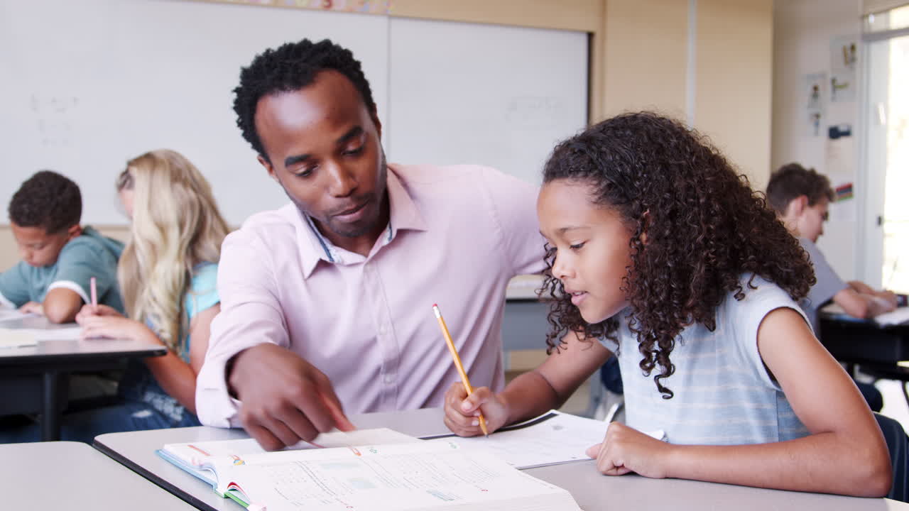Male elementary school teacher working in class with girl