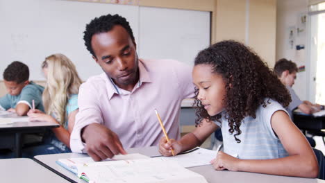 male elementary school teacher working in class with girl