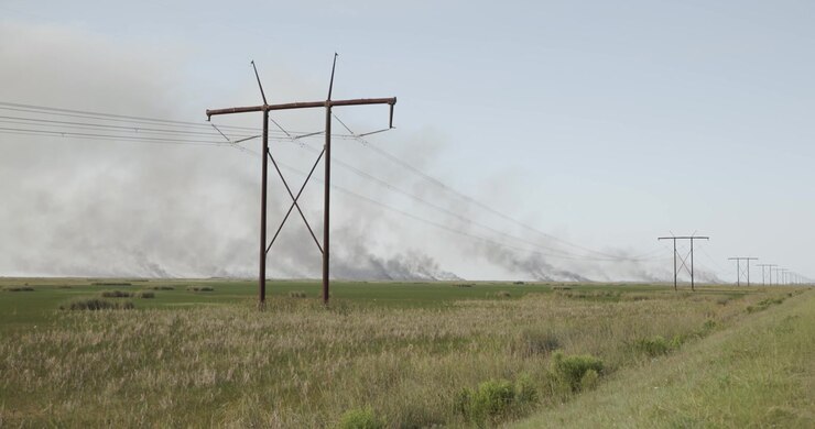 4K footage of multiple wildfire hotspots burning across the Florida Everglades in Broward County. Smoke rises beyond sawgrass marshes, Powerlines in foreground.