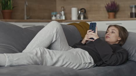 Mujer-Caucásica-Relajándose-En-El-Sofá-Y-Usando-El-Teléfono-Móvil.