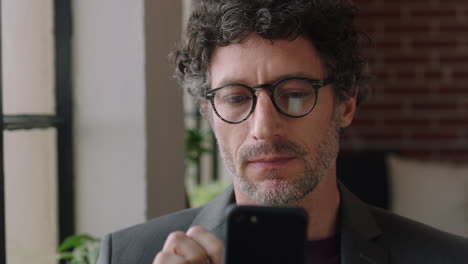 retrato hombre de negocios maduro usando un teléfono inteligente en casa escribiendo mensajes de correo electrónico en línea conectándose en redes sociales disfrutando de la comunicación por teléfono móvil mirando por la ventana planeando hacia adelante usando gafas