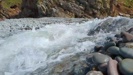 río de agua blanca corriendo en cámara lenta en la playa rocosa