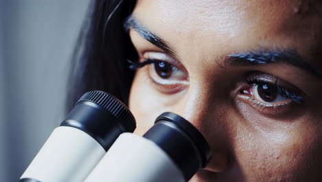 close-up of a scientist looking through a microscope