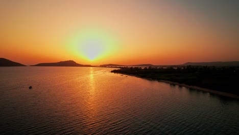 Una-Gran-Bola-Amarilla-De-Sol-Extiende-Una-Luz-Degradada-De-Tono-Rojo-Dorado-Por-Todo-El-Océano-Y-El-Cielo,-Pylos-Grecia