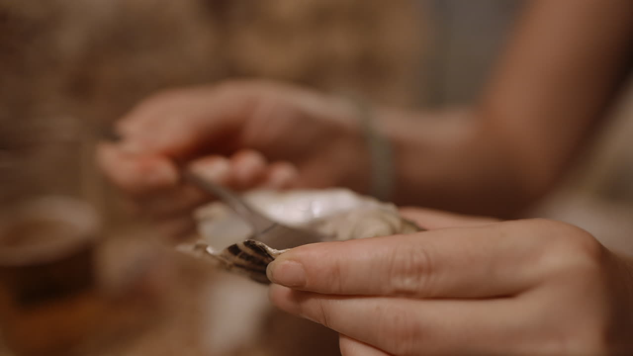 A close-up of hands eating an oyster