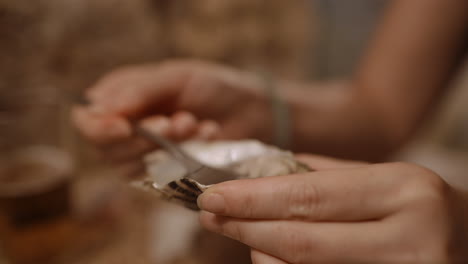 a close-up of hands eating an oyster