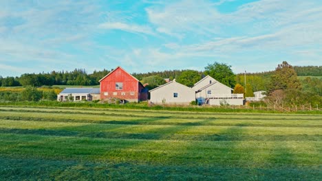 farmhouse and barn surrounded with green fields in norway - drone shot