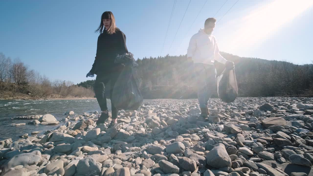 해변에서 플라스틱을 청소하는 팀워크: 자원봉사자들이 쓰레기 봉투에 쓰레기를 모으고, 플라스티크 오염과 환경 문제 개념: 플래스틱에서 자연을 자발적으로 청소하는 것, 지구를 녹색화하는 것