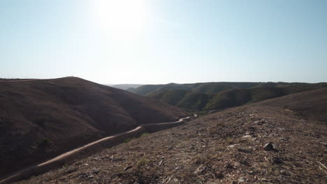 colinas áridas y secas y paisajes ásperos en el algarve, portugal - empujar la grúa hacia arriba