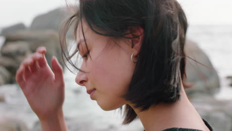 portrait of beautiful asian woman smiling enjoying cloudy seaside exploring vacation lifestyle with wind blowing hair on beach