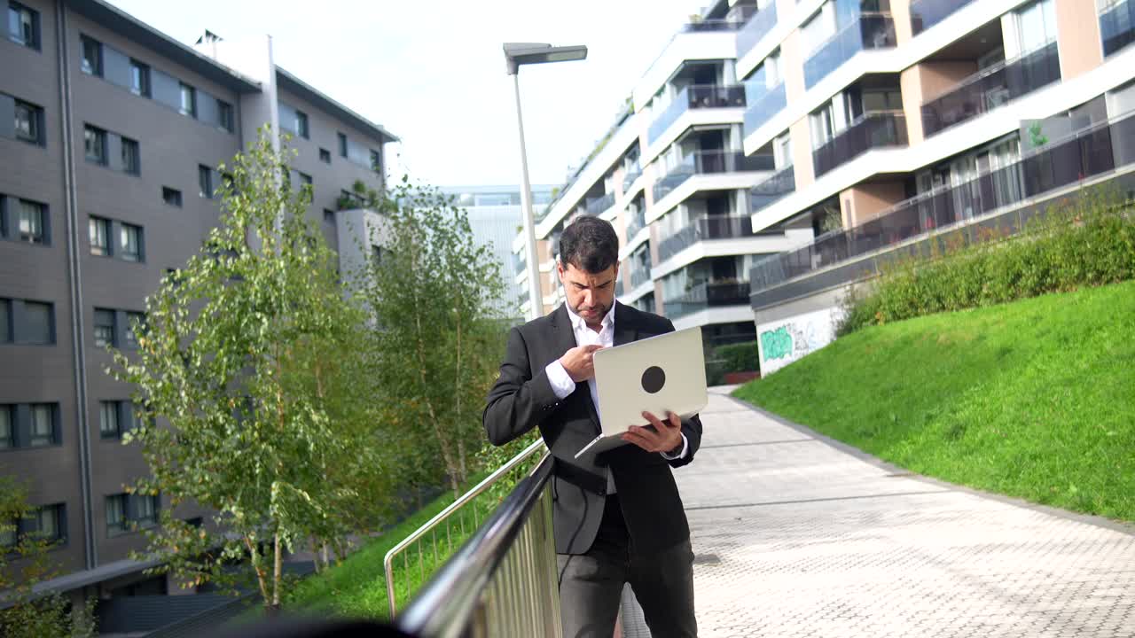 Professional man using a laptop outdoors in an urban environment