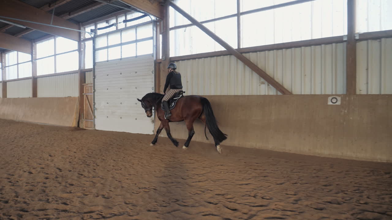 Slow motion shot of a woman riding a horse in riding stablev