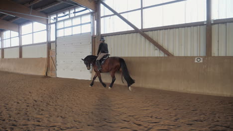 slow motion shot of a woman riding a horse in riding stablev