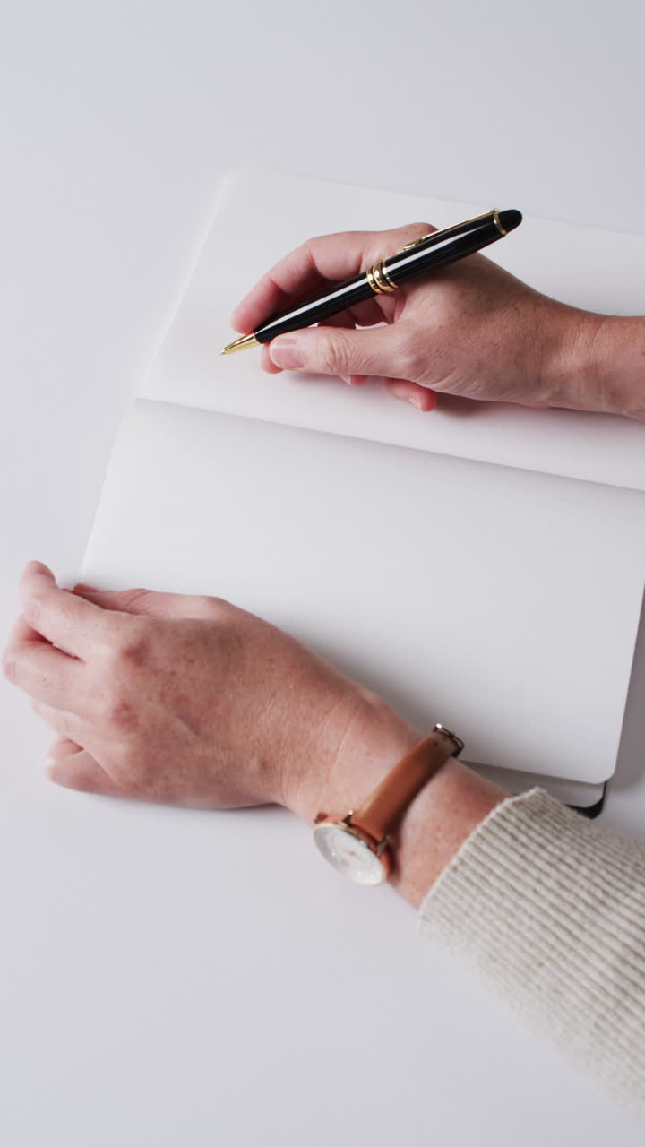Video verticale di mano che scrive con una penna su un libro con spazio per il testo su sfondo bianco al rallentatore