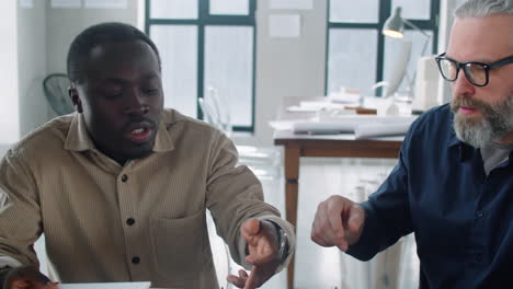 black architect discussing building model with senior caucasian colleagues