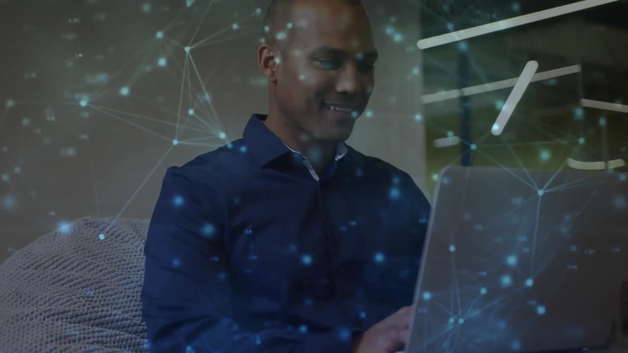 Animation of communication network over smiling biracial man using laptop in office