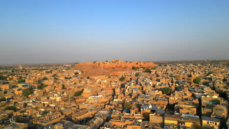 una impresionante toma lateral de drone del fuerte de jaisalmer, destacando su majestuosa arquitectura en medio de las casas de tonos dorados de la ciudad capturada en un día soleado en rajasthan, india