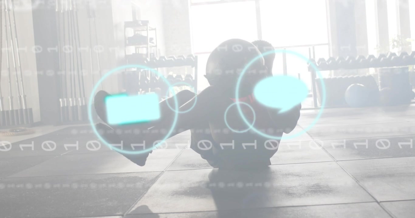 Male athlete lifting ball into sit-up in gym for core training, pulsing digital interface icons