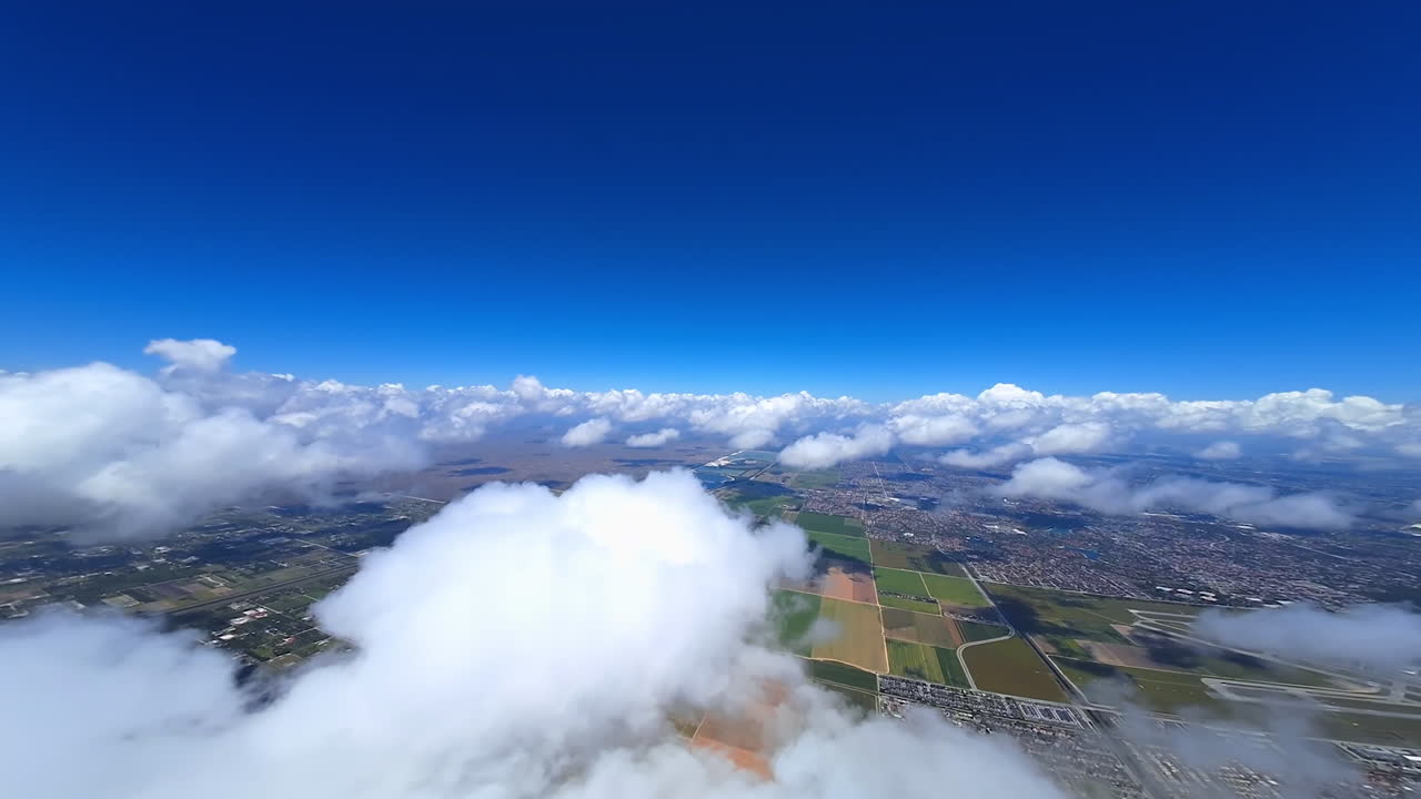 Lovely fluffy clouds hanging in the sky. FPV drone turns in the cloudscape revealing the view on the city view below.