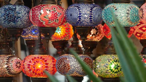 colourful turkish lamps from glass mosaic glowing. arabic multi colored authentic retro style lights. many illuminated moroccan craft lanterns. oriental islamic middle eastern decor. shiny folk shop