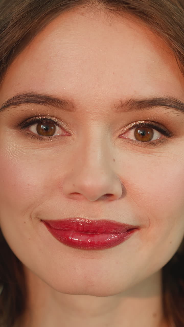 Portrait of attractive curly-haired woman on blurred background. Young redhead female with glamorous makeup looks in camera smiling with open eyes closeup