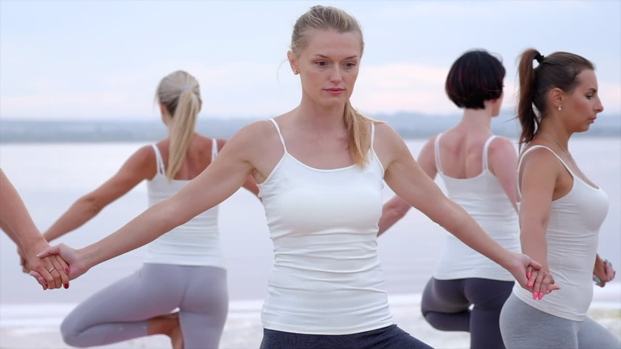 6명의 40대 백인 여성들이 원으로 서서 나무 포즈를 연기하고 있다.