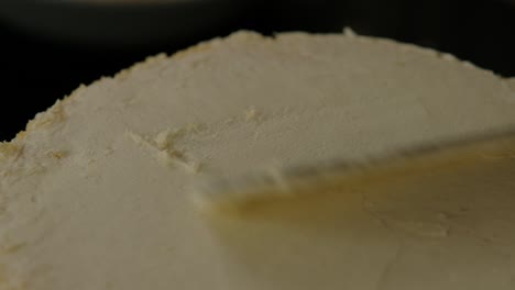 close-up of frosting the top of a vanilla cake with a spatula