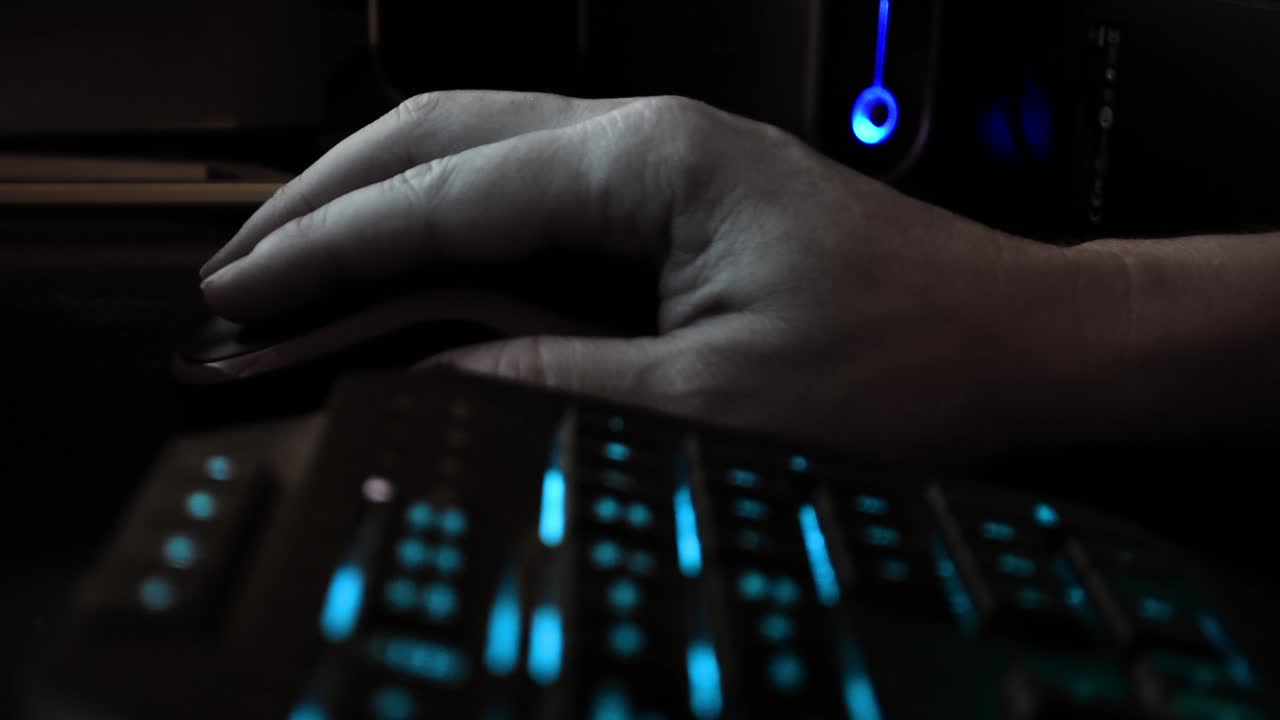 cerrar la mano de un hacker usando un ratón de computadora, oficina oscura