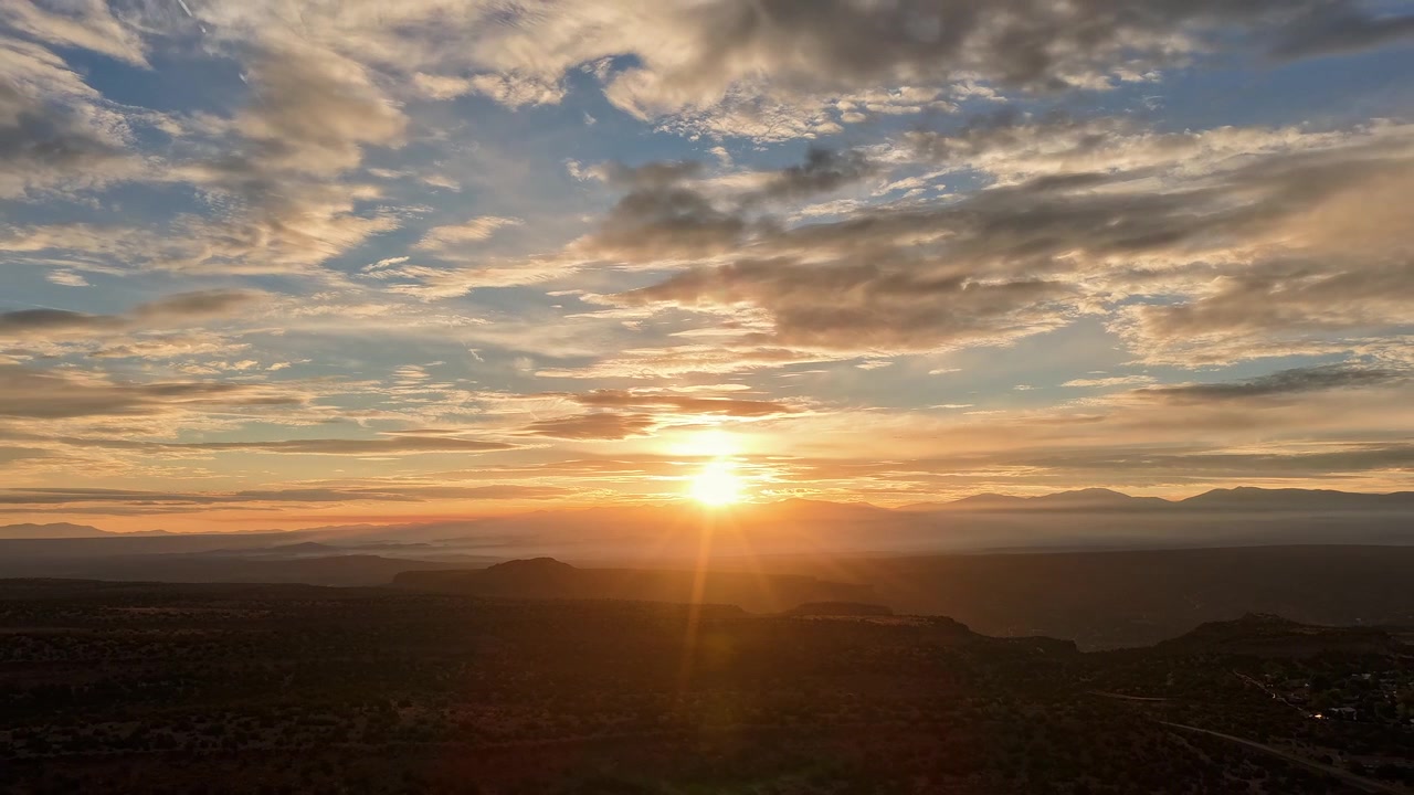 Un hyperlapse 4K da drone di uno splendido skyline del Sud-Ovest con bellissime nuvole stratificate all'alba, che proietta una luce dorata sulle mesa con il traffico mattutino visibile sotto