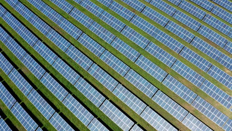 rows of solar panels in a green field seen from above on a sunny day
