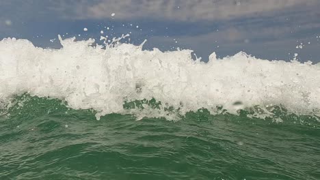 water surface point of view of old bearded active man with arms wide open waiting big sea waves splashing on him