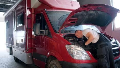 mechanic working on a red van's engine in a garage