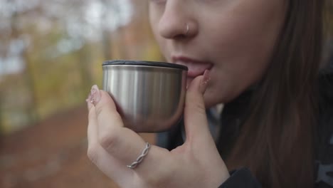 woman drinking coffee or tea in the autumn forest