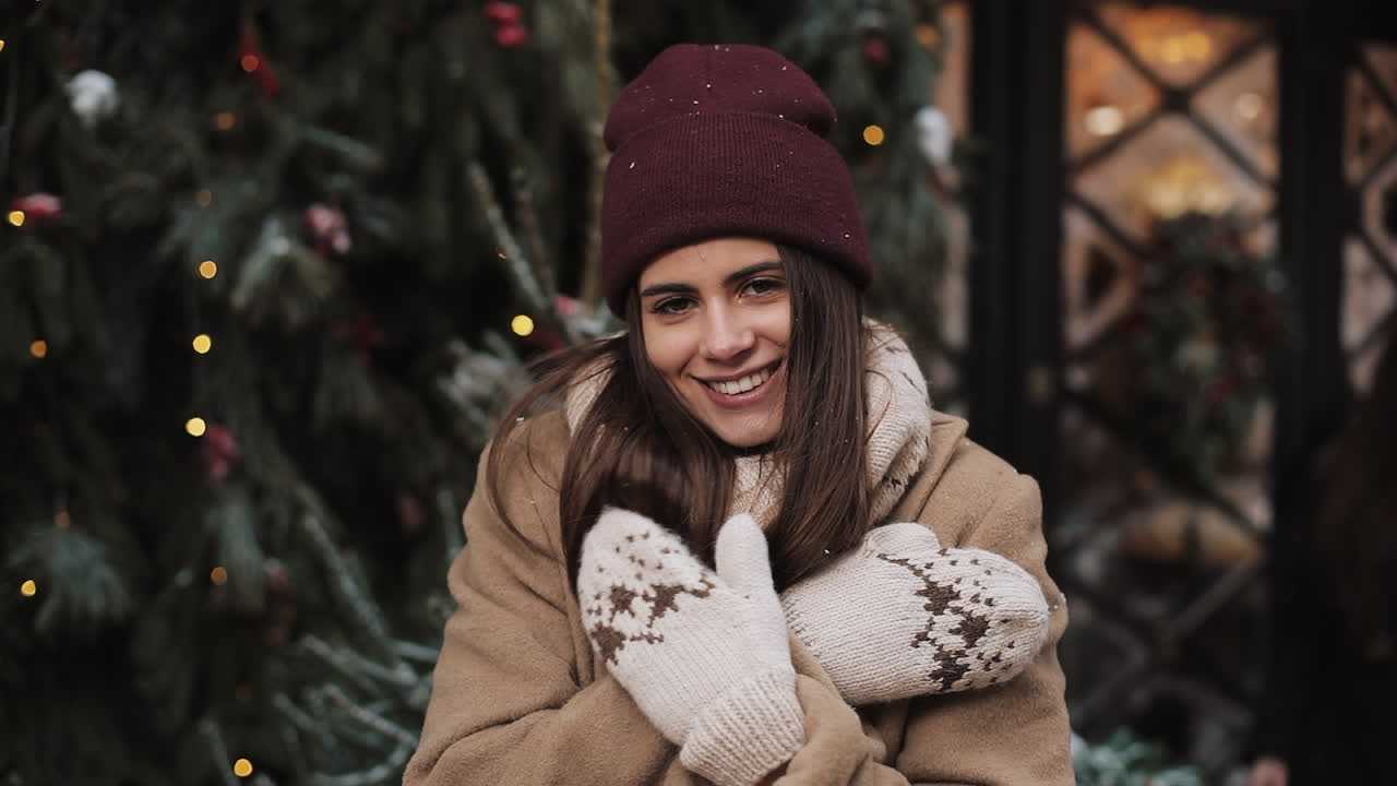 Woman in winter clothing posing near Christmas tree