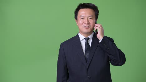 mature japanese businessman against green background