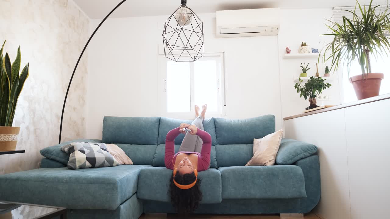 caucasian woman listening to music with her headphones lying on the sofa