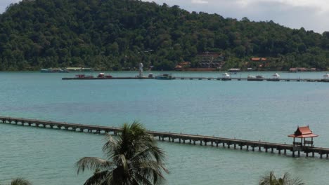 static shot of 2 piers in the ocean, one with red roofs and one with boats crop slowmo