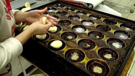 bakers lay out the dough buns on a baking tray