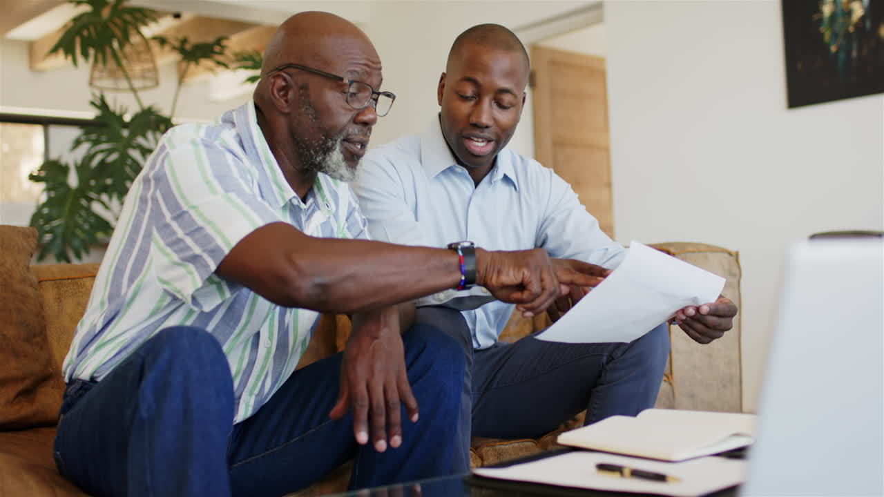 Discussing documents, financial advisor and client sitting on couch, collaborating on work
