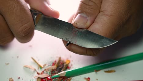 Footage-of-hands-slowly-sharpening-a-pencil-and-some-coloured-pencils-with-a-sharp-knife