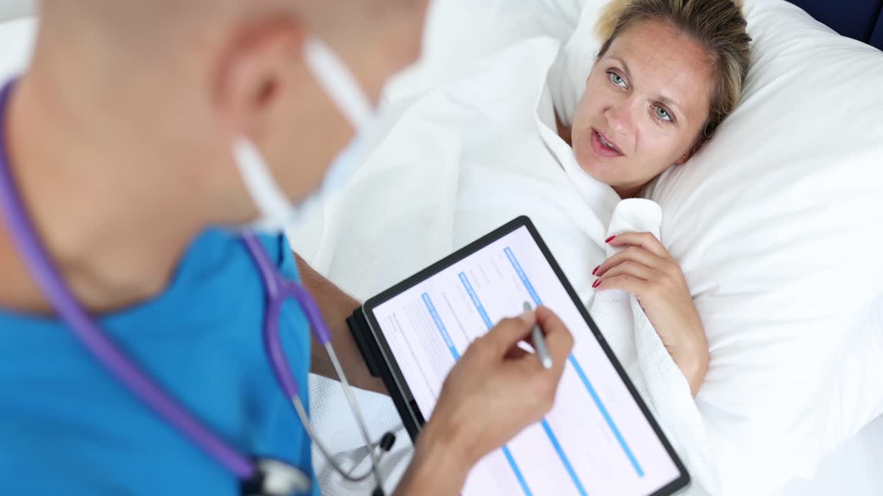 Medical Professional Consulting Patient in Hospital Bed with Tablet