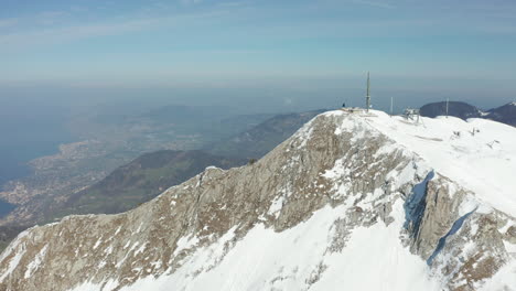 aerial of tall radio tower on top of snow covered mountain