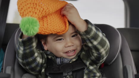 two-year-old asian kid has fun in a child car seat. playing hide and seek in the back seat of a car