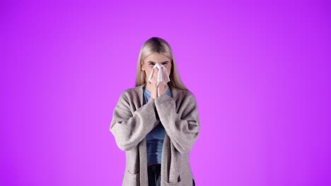 concept having the flu or cold, woman blows and cleans nose, isolated purple