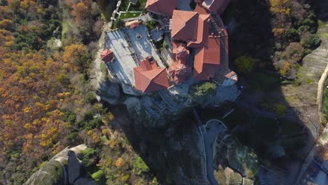 4K-Meteora-Monestary-of-Varlaam-Birds-eye-View-looking-Down-Meteora-Greece,-Pillar-Rock-Formations,-Fall-colors-at-Sunset,-Ancient-Greece,-Wonders-of-the-World,-Cinematic,-Man-walking-between-building