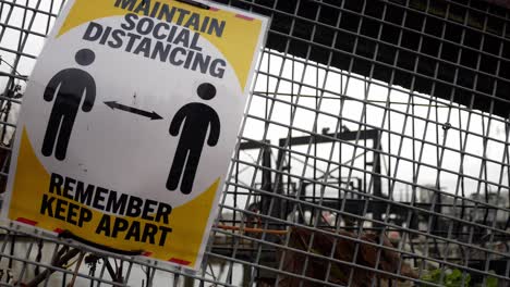 Corona virus maintain distance warning information sign on metal fence closeup dolly right