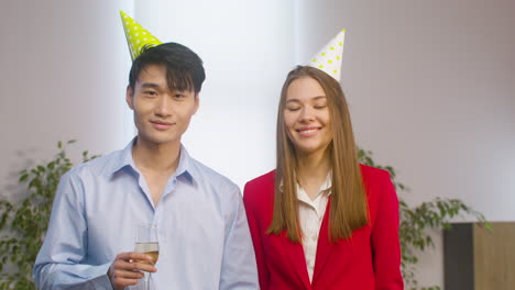 portrait of an young man with champagne glass and a girl smiling and looking at camera at the office party