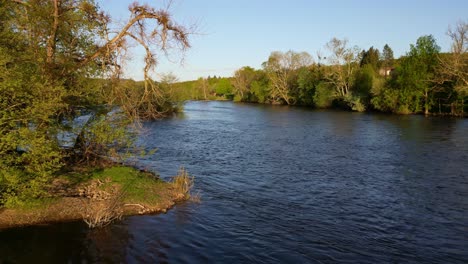 Drone-flying-at-low-altitude-over-Vienne-river-in-Saint-Victurnien-countryside,-Nouvelle-Aquitaine-in-France